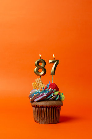 birthday cake with number 87 - cupcake on orange background with birthday candlesの写真素材