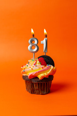 birthday cake with number 81 - cupcake on orange background with birthday candlesの写真素材