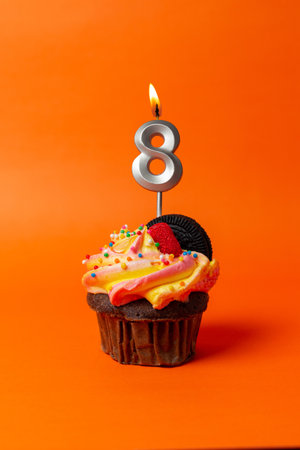 birthday cake with number 8 - cupcake on orange background with birthday candlesの写真素材