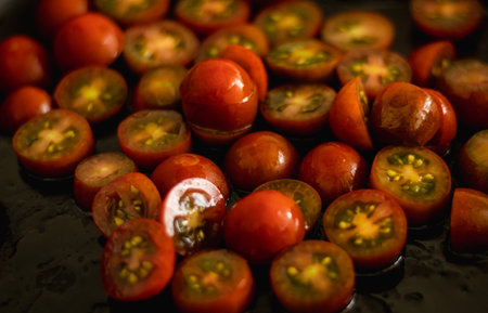 Cherry tomatoes cut into slices, with a dark background.の写真素材