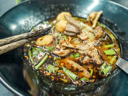 Spicy pork noodles in a black bowlの写真素材