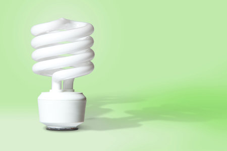 Compact fluorescent light bulb with shadows on light green background with room for copy 