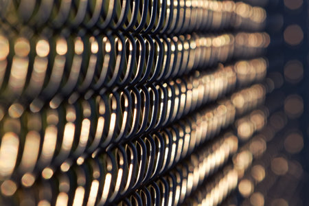 Artistic abstract view of black chain link fence in  late afternoon, early evening sunlight.