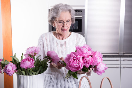 Female senior is putting flowers into vase