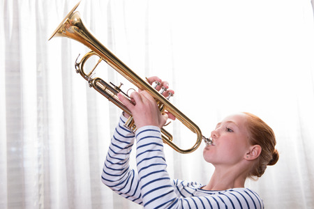 red haired teenage girl playing the trumpetの写真素材