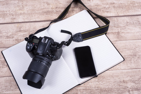Photographers workplace with book, phone  and camera on wooden table