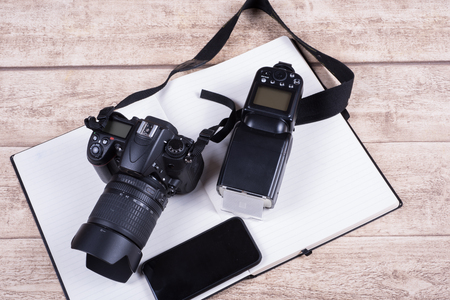 Photographers workplace with book, phone  and camera on wooden tableの写真素材