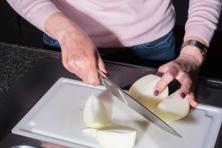 woman is cutting big onions in the kitchenの写真素材