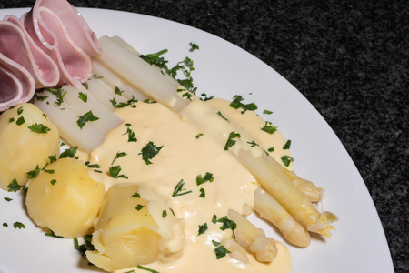 cooked white asparagus with potatoes, parslay and hamの写真素材