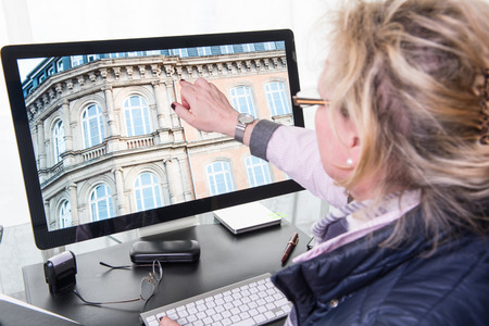female architect pointing to part of project on big computer screenの写真素材