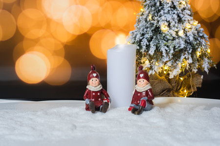 Candle and figures with Christmas tree against light backgroundの写真素材