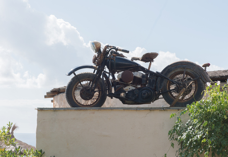 rusted motorcycle on a roof in the back lightの写真素材