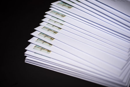 Stack of franked letters in white envelopes on black background