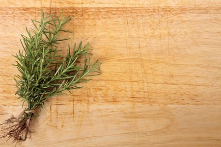 Bunch of fresh rosemary on an old wooden chopping board. Space for copy.の写真素材