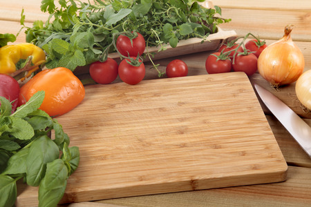 Herbs and vegetables with a blank chopping board. Space for copy.の写真素材