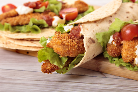 Making deep fried chicken fajita wrap sandwich with stack of tortillasの写真素材