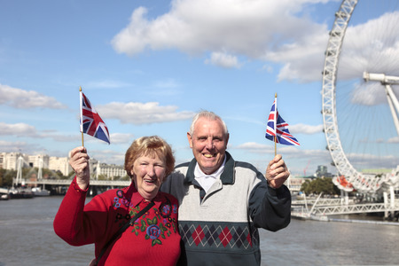 Senior couple holding British flag in London with Millenium wheel in the backgroundの写真素材