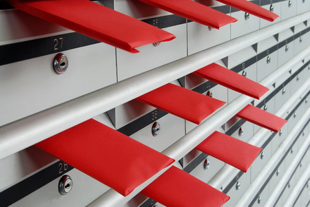 Letterboxes in rows with letters in red envelopesの写真素材