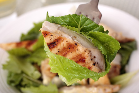 A piece of chicken caesar salad on the forkの写真素材