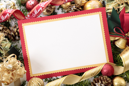 Blank Christmas card or invitation with red envelope surrounded by decorations. Space for copy.の写真素材