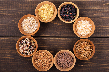 Variety of rice and grains in bowls on wooden tableの写真素材