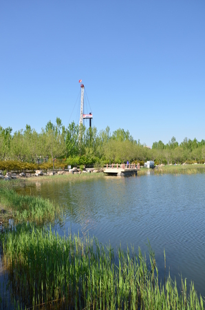 View of a lake with a drilling rig in the backgroundのeditorial素材