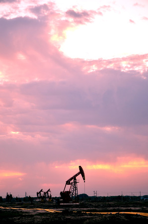 Oil pump jacks in a field under sunset skyのeditorial素材