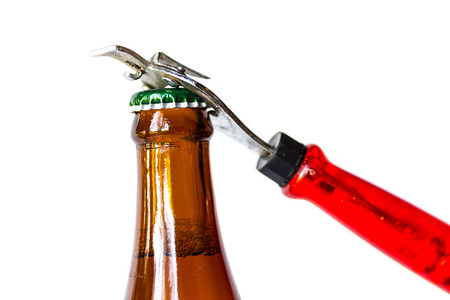 Opening dark beer bottle with metal openerの写真素材