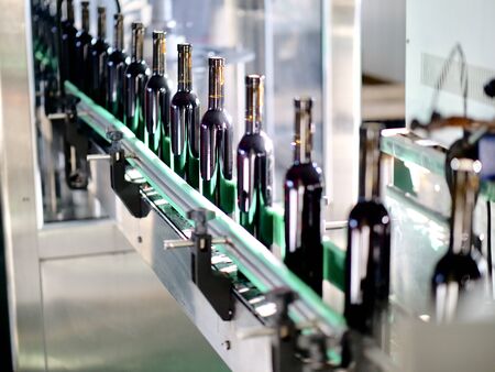 the filled red wine bottles is being produced on the assembly line