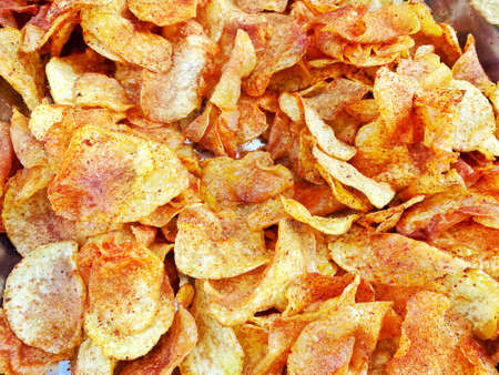 Delicious fried potato chips, sliced yellow crispy snacks, spicy potato snacks with spice, unhealthy...