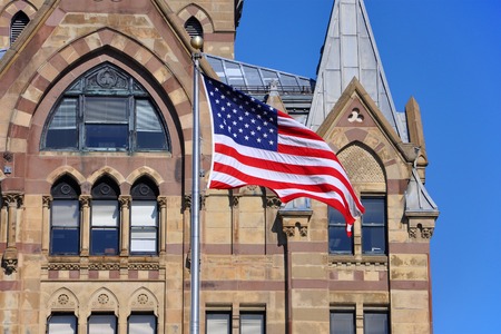 US National Flag in front of Syracuse Savings Bank Building at Clinton Square in downtown Syracuse, York State, USA.のeditorial素材