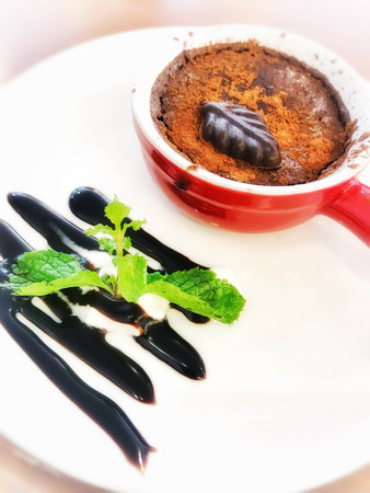 Quick chocolate coffee cake in a red cup on a white plate.の写真素材