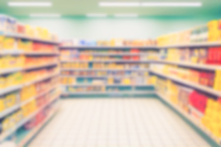 Abstract blurred background supermarket aisles with colorful shelves of merchandise. Perspective view of supermarket aisle with copy space in center, can use as background or retail conceptの写真素材