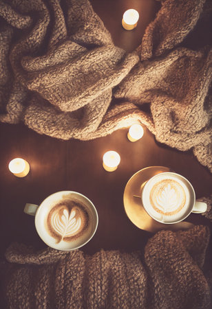 Cozy winter or autumn morning at home. Swedish hygge includes hot coffee with a gold metallic spoon, a warm blanket, a garland, and candle lights.Â 3D illustrationの写真素材
