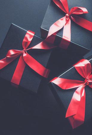 Top view of black Christmas boxes with red ribbon on a black background with copy space for text. Composition of Black Friday and Boxing Day.Â 3D illustrationの写真素材