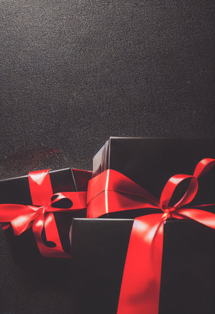 Top view of black Christmas boxes with red ribbon on a black background with copy space for text....