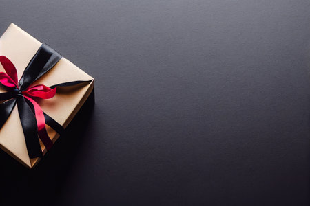 Top view of black Christmas boxes with red ribbon on a black background with copy space for text. Composition of Black Friday and Boxing Day.Â 3D illustrationの写真素材