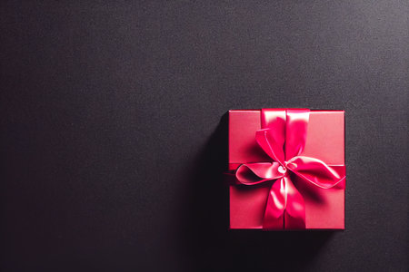 Top view of black Christmas boxes with red ribbon on a black background with copy space for text. Composition of Black Friday and Boxing Day.Â 3D illustrationの写真素材