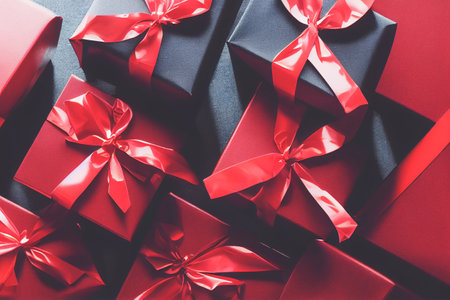 Top view of black Christmas boxes with red ribbon on a black background with copy space for text. Composition of Black Friday and Boxing Day.Â 3D illustrationの写真素材