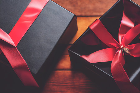 Top view of black Christmas boxes with red ribbon on a black background with copy space for text. Composition of Black Friday and Boxing Day.Â 3D illustrationの写真素材