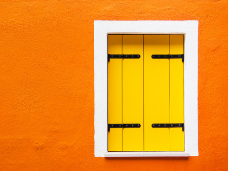 Closed yellow shutters on the ancient orange wall of the house - Burano, Venice, Italy の写真素材