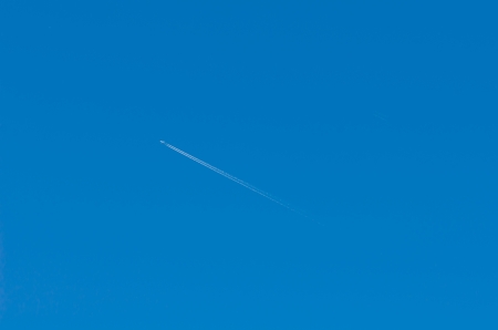 airplane flies in white clouds in a blue sky and leaving trail