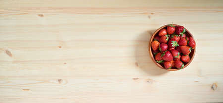 Strawberries with strawberry leaf on a Wooden bowl on wooden board.の写真素材