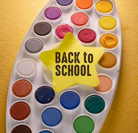 Back to school concept. On a yellow background, a palette of watercolors.の写真素材