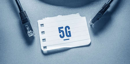 The word 5G is written on a piece of paper lying on a blue background.
