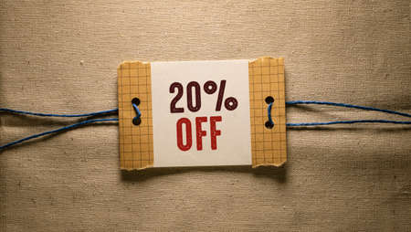20 percent off sign on a piece of paper on a linen background