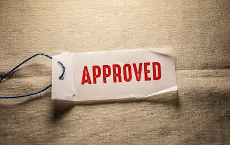 Approved word on a piece of paper on burlap backgroundの写真素材