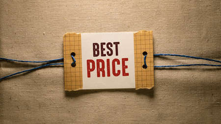 Text sign showing Best Price. Conceptual photo the lowest price of a product or service which is usualy available Piece of torn cardboard placed above a wooden classic table backdropの写真素材