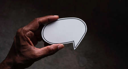 Close-up of a male hand holding a paper speech bubble.の写真素材
