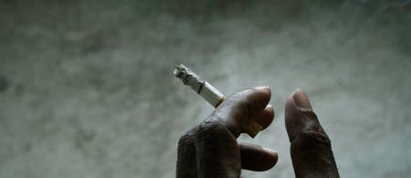 Closeup of cigarette butt with poor man hand
